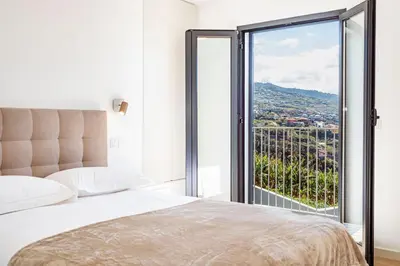 a bedroom with a bed and a large window at Cocoon House in Canhas