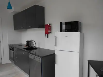 a kitchen with a white refrigerator and black cabinets at Holiday Apartments Funchal - Bouganvilla in Funchal
