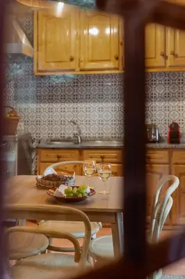 a kitchen with a table with a plate of fruit and wine glasses at A refuge in nature - Chalet D'Avó Teresa in São Vicente