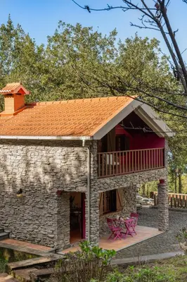 a stone house with a balcony and a deck at A refuge in nature - Chalet D'Avó Teresa in São Vicente