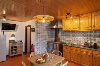 a kitchen with wooden cabinets and a table and a stove at A refuge in nature - Chalet D'Avó Teresa in São Vicente