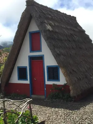 a house with a thatched roof and a red door at Holiday apartments Funchal - Rosemary in Funchal