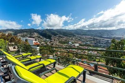 a row of yellow chairs on a balcony with a view at Casa Barcelos View in Funchal