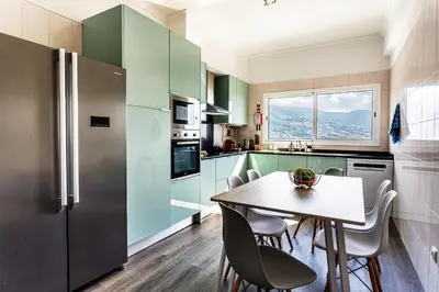 a kitchen with green cabinets and a table and chairs at Casa Barcelos View in Funchal