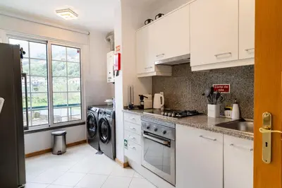 a kitchen with white cabinets and a washer and dryer at GuestReady - Scenic Retreat with Stunning Views in São Vicente