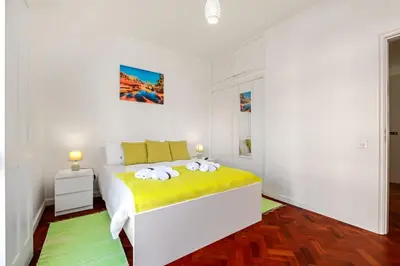 a white bedroom with a bed with yellow sheets at Quinta Paraiso in Funchal