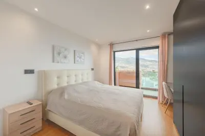 a white bedroom with a bed and a window at Best View Funchal Vacation Apartment in Funchal
