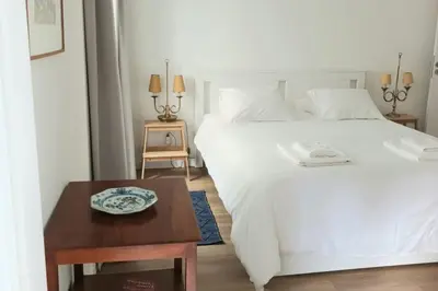 a bedroom with a white bed and a wooden table at Alamos Charming Apartments - Family in Funchal