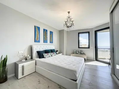 a white bedroom with a bed and a chandelier at Endless Holiday 2 Bedroom Apartment Lido in Funchal