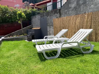 two white lounge chairs sitting in the grass at Amélia's House in Seixal
