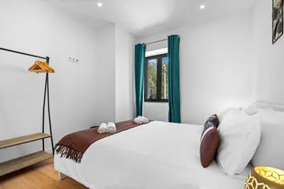 a bedroom with a white bed and a window at Casa da Cristina in Santa Cruz