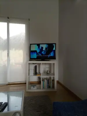 a living room with a flat screen tv on a white shelf at Vivenda Nina in Porto Santo