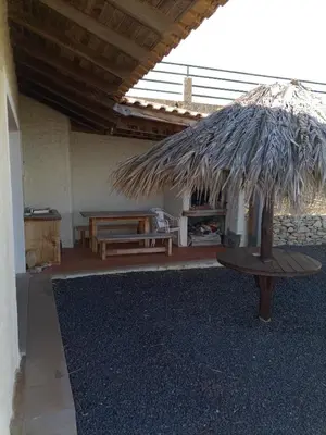 a patio with a table and a straw umbrella at Vivenda Nina in Porto Santo