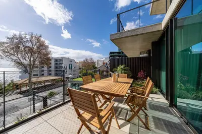 a patio with a wooden table and chairs on a balcony at Savoy Residence Monumentalis 2B or Not 2B by LM&AC Signature in Funchal