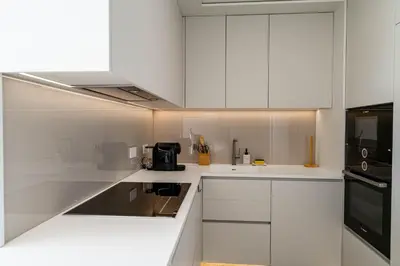 a white kitchen with white cabinets and a black appliance at Savoy Residence Monumentalis 2B or Not 2B by LM&AC Signature in Funchal