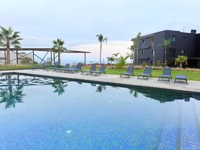 a swimming pool with lounge chairs in front of a building at Virtudes Charm in Funchal