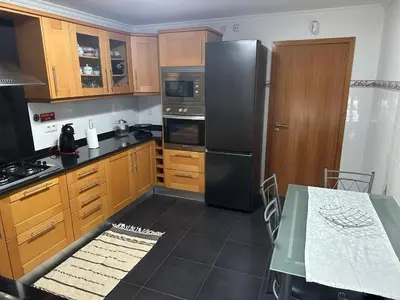 a kitchen with wooden cabinets and a black refrigerator at Sea View Andrade 3 Bedroom House in Gaula