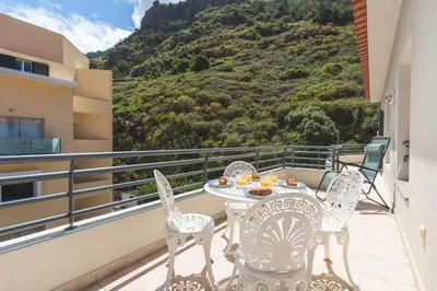 a balcony with a chair and a view of a mountain at HappyStay by Atlantic Holiday in Ribeira Brava