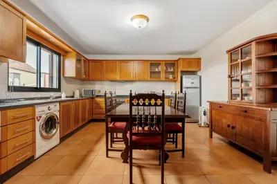 a kitchen with wooden cabinets and a table and chairs at Casa Rocha in Fajã da Ovelha