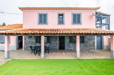 a house with a patio and a green lawn at Casa Rocha in Fajã da Ovelha