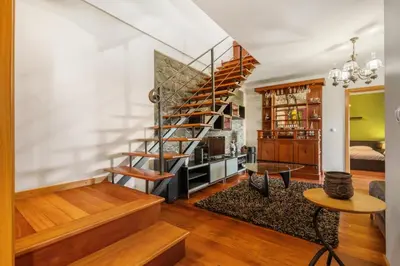 a living room with a spiral staircase and a table at Casa Rocha in Fajã da Ovelha