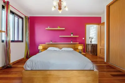 a bedroom with a large bed with a pink wall at Casa Rocha in Fajã da Ovelha