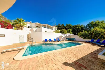 a swimming pool with chairs and a house in the background at 180 degree Ocean Views, Pure Paradise in Luz