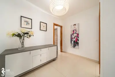a white room with a vase of flowers on a cabinet at 180 degree Ocean Views, Pure Paradise in Luz