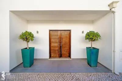 two green vases with trees in them in front of a door at 180 degree Ocean Views, Pure Paradise in Luz
