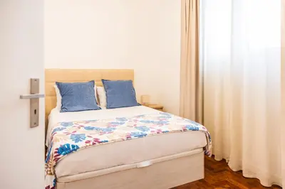 a bedroom with a bed with blue pillows and a window at Porto Santo Beach Side Oasis in Vila Baleira