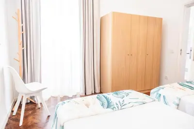 a bedroom with two beds and a wooden cabinet at Porto Santo Beach Side Oasis in Vila Baleira