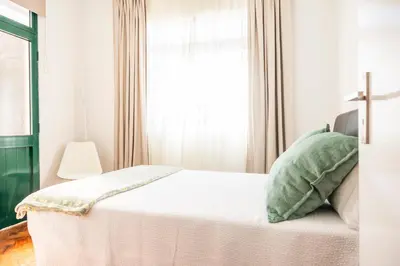 a white bedroom with a bed with a window at Porto Santo Beach Side Oasis in Vila Baleira