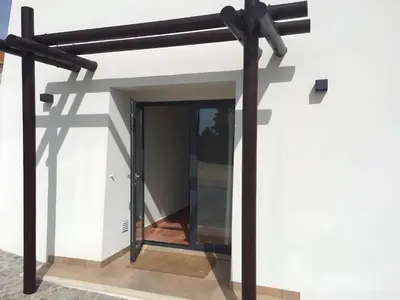 a modern house with a glass door and black beams at Amado Properties in Carrapateira