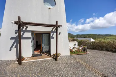 a bedroom with a bed and a table and a chair at Amado Properties in Carrapateira