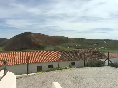 a view of a house with a mountain in the background at Amado Properties in Carrapateira