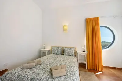 a small bedroom with a bed and a window at Amado Properties in Carrapateira