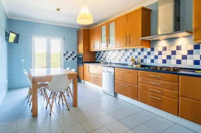 a kitchen with wooden cabinets and a table with chairs at The Suites by The Lighthouse Arrifana in Aljezur