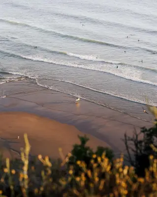a view of the beach with people in the water at The Suites by The Lighthouse Arrifana in Aljezur