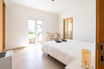 a white bedroom with a bed and a window at The Suites by The Lighthouse Arrifana in Aljezur