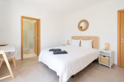 a bedroom with a large white bed and a desk at The Suites by The Lighthouse Arrifana in Aljezur