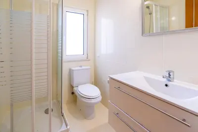 a white bathroom with a toilet and a sink at The Suites by The Lighthouse Arrifana in Aljezur