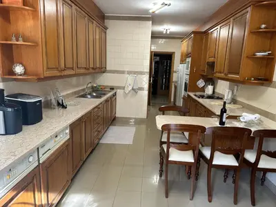 a kitchen with wooden cabinets and a table and chairs at 2 Madeira Inn Group in Funchal