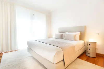 a white bedroom with a large bed and a window at NÔNA Suite Funchal in Funchal
