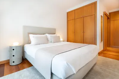 a bedroom with a large white bed and a wooden cabinet at NÔNA Suite Funchal in Funchal
