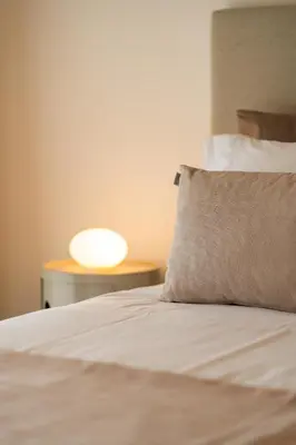 a bed with a pillow and a lamp on a table at NÔNA Suite Funchal in Funchal