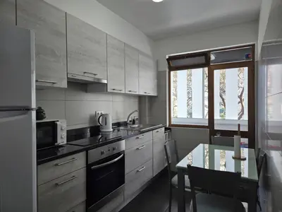 a kitchen with white cabinets and a table and a window at The Infante Stay in Funchal