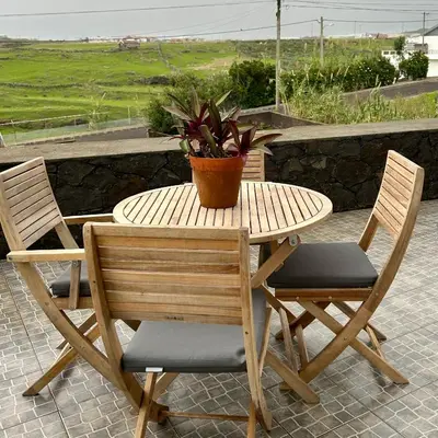 a wooden table with two chairs and a potted plant at Casa da Avó - Vila do Porto in Vila do Porto