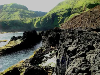 a rocky shore with a mountain in the background at Casa da Avó - Vila do Porto in Vila do Porto