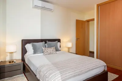 a bedroom with a bed and two lamps and a door at Private pool and sea view - Tropical Villa in Arco da Calheta