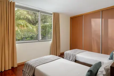 a hotel room with two beds and a window at Private pool and sea view - Tropical Villa in Arco da Calheta